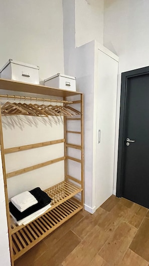 A room with a wooden shelf unit, a white wardrobe, and a dark door. - FER’s SPOT beautiful studio/apartment downtown Madrid close to all imprtnt spots (Madrid)