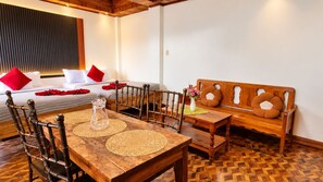 Una habitación con una mesa de comedor de madera, sillas, un sofá y una cama con almohadas rojas.