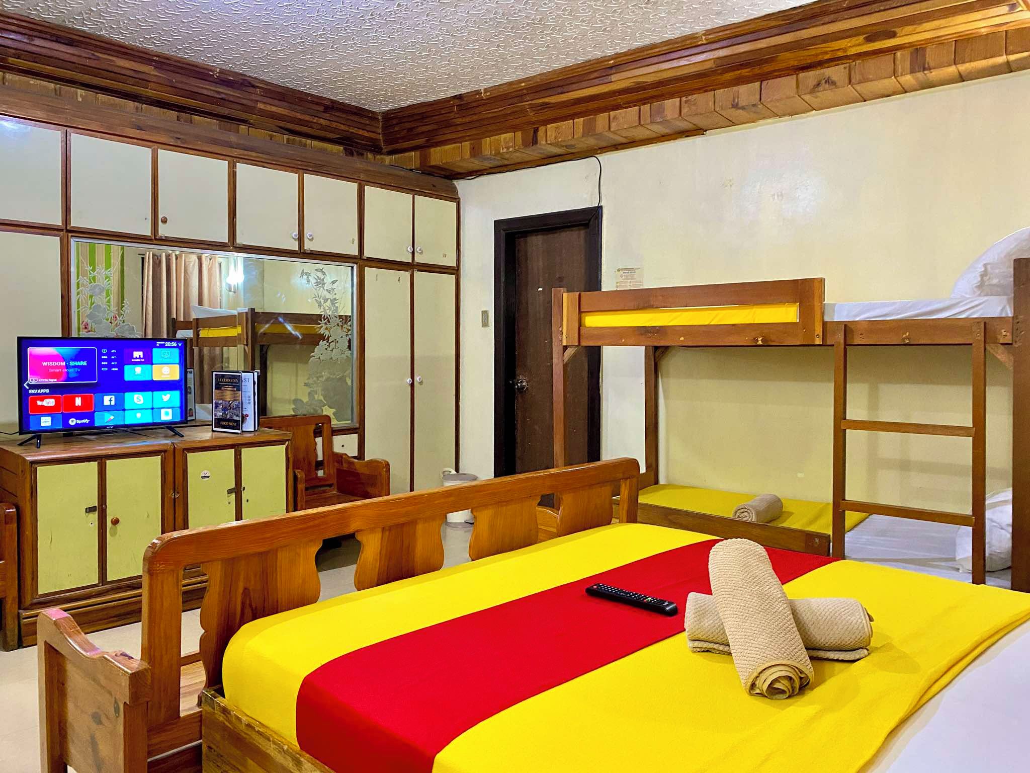 A hotel room with bunk beds, a television, a desk with a computer, and a chair.