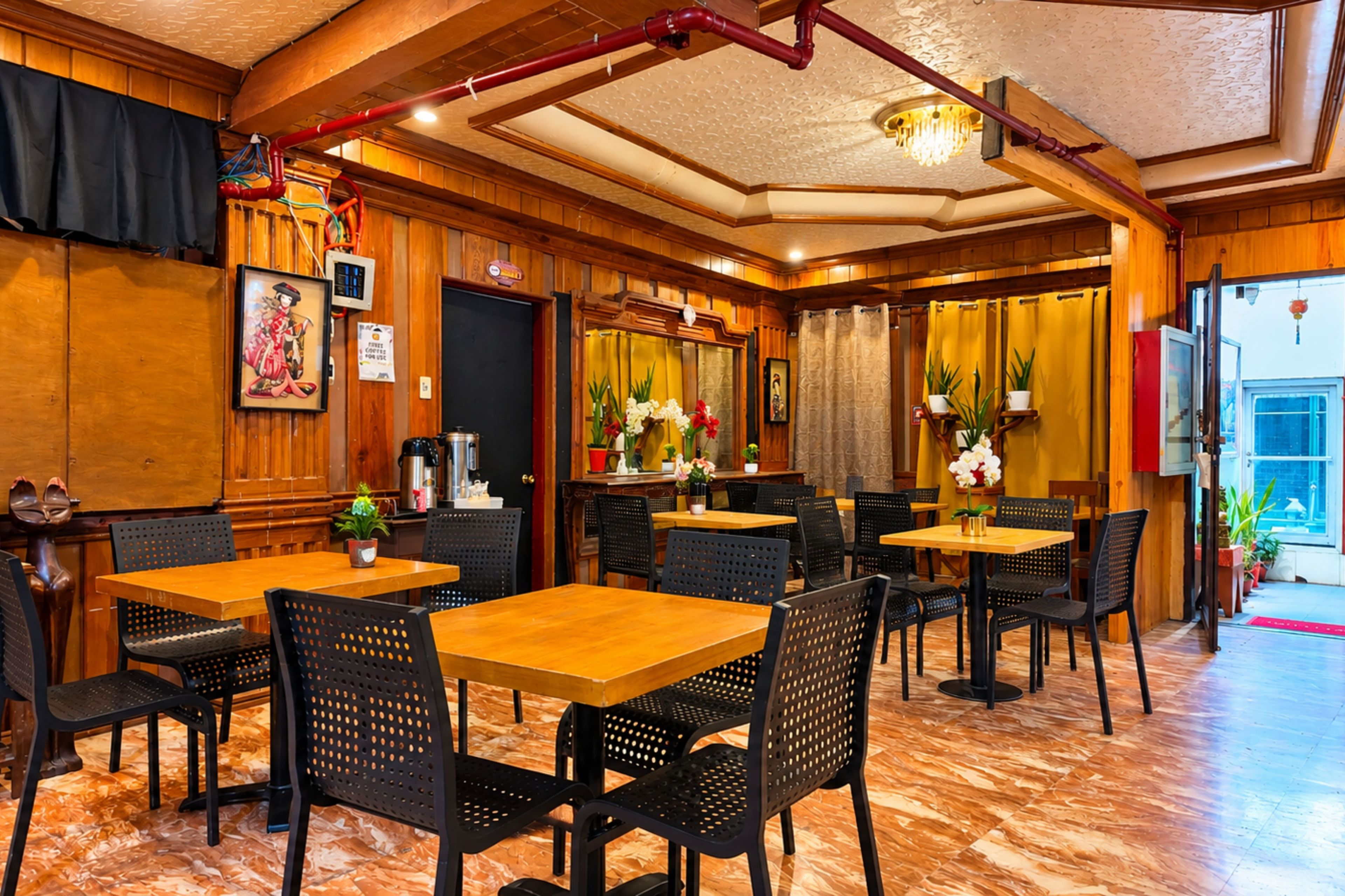 A restaurant interior with wooden paneling, black perforated chairs, and a marble floor.