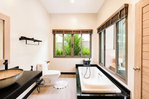 Een moderne badkamer met een groot raam, een badkuip en een toilet.
