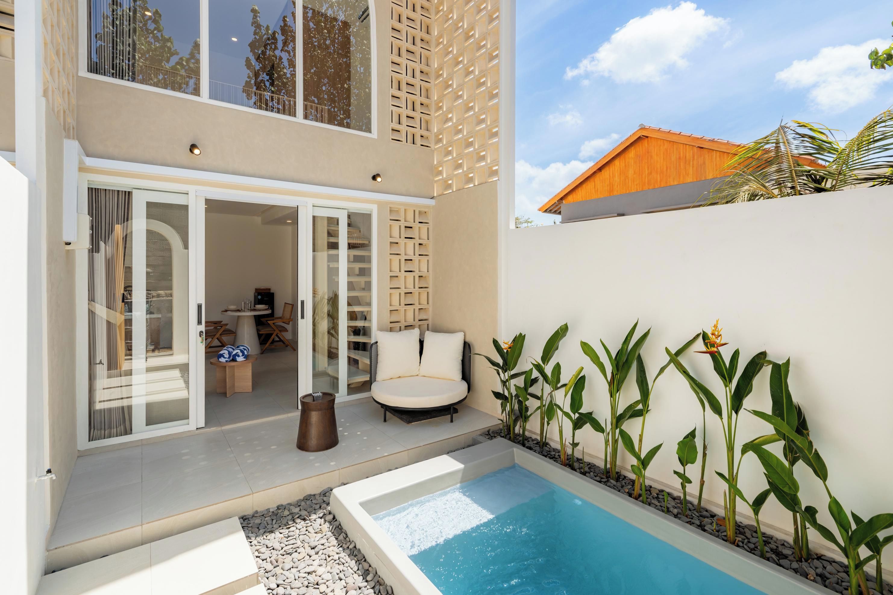 Un espace piscine extérieur moderne, doté d’un coin salon et offrant une vue sur un immeuble d’habitation.