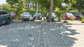 A parking area with paved ground, metal barriers, and parked cars. - LB - Balcsikuckó Apartman (Siófok)