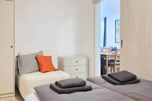 Une chambre à coucher comprenant un lit, une table de chevet, une commode et donnant sur un espace extérieur.