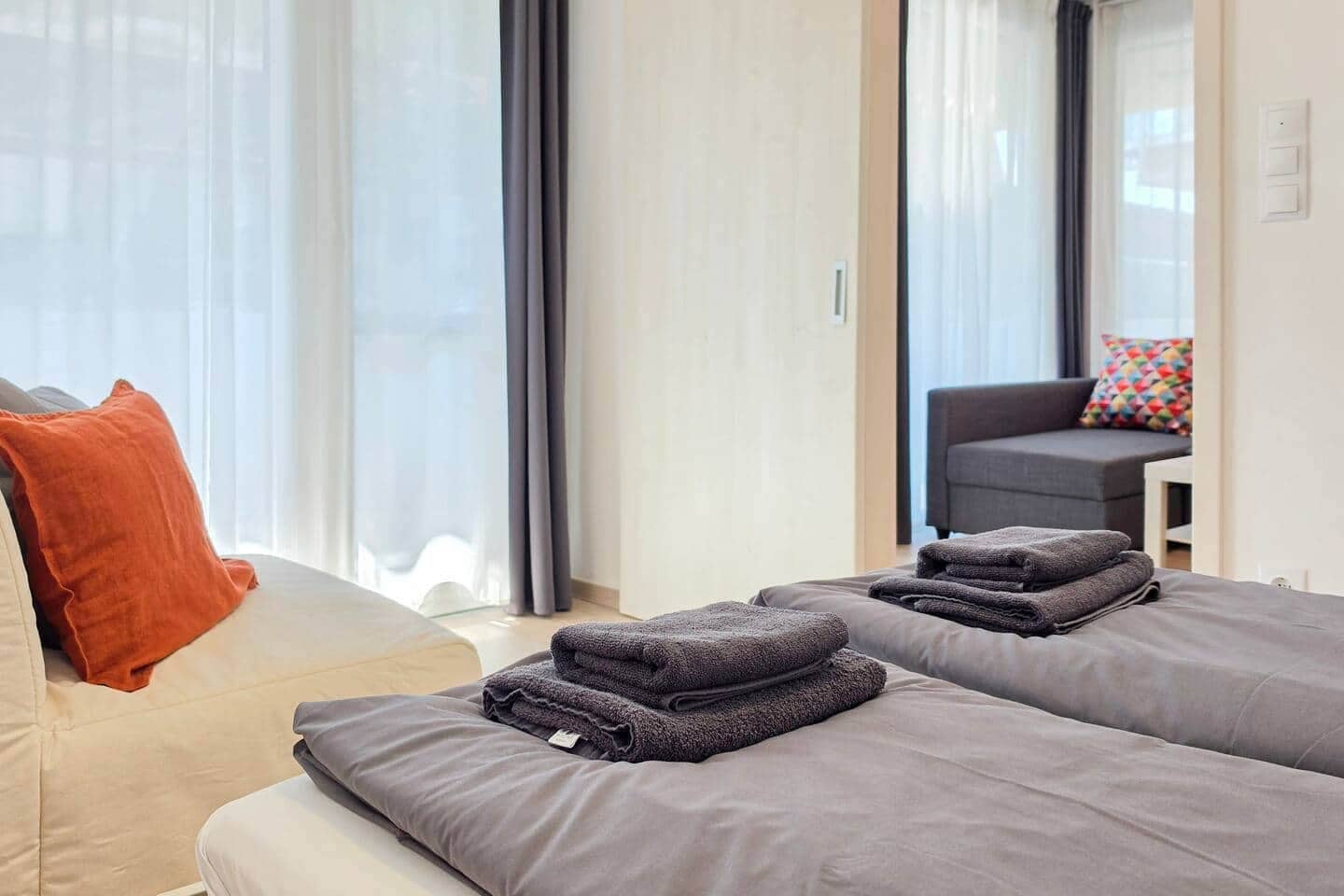 Une chambre d’hôtel avec deux lits, un canapé, une chaise et une petite table.