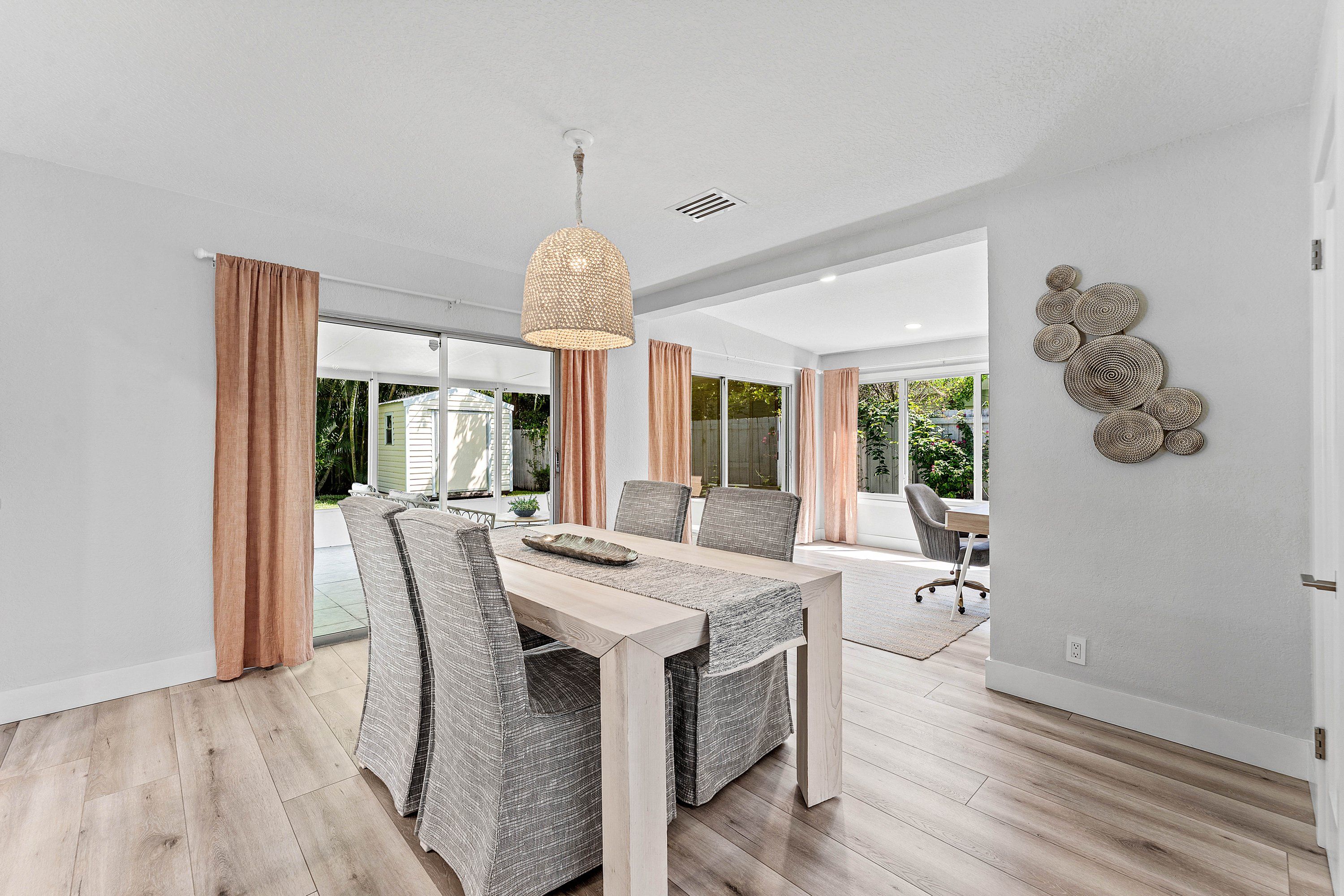 Un espace repas moderne avec une table en bois, des chaises à motifs et un luminaire suspendu.