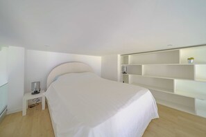 Ein Schlafzimmer mit einem Bett, einem Nachttisch, einer Lampe und eingebauten Regalen.