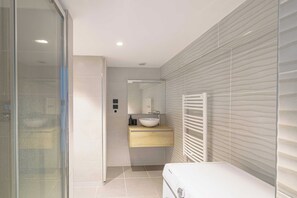 Ein modernes Badezimmer mit einer Duschkabine aus Glas, einem weißen Waschbecken und einem integrierten Handtuchhalter.