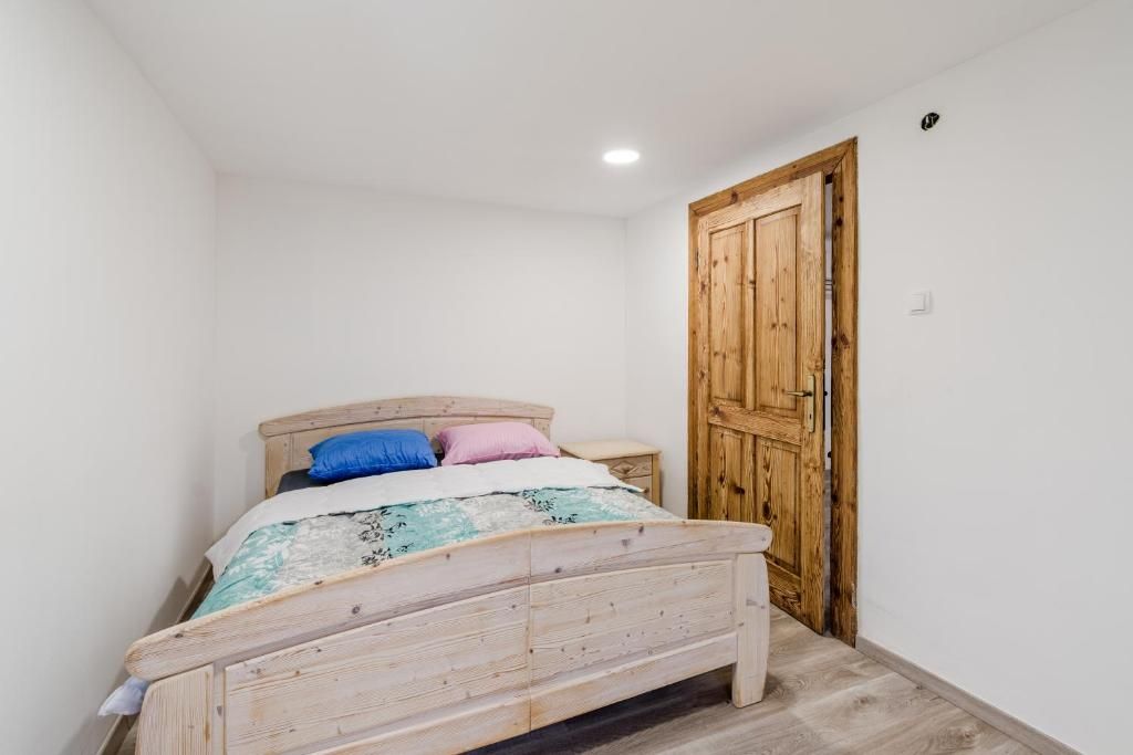 Une chambre à coucher avec un lit en bois, une table de chevet et une armoire en bois.