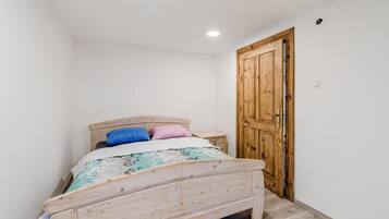 Une chambre à coucher avec un lit en bois, une table de chevet et une armoire en bois.