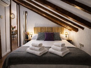 A hotel room with a bed, two bedside tables, a wooden ceiling, and a view of a dining area. - Penthouse Near Plaza Mayor, Madrid (Madrid)