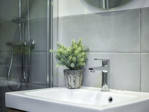 A bathroom with a white sink, a potted plant, and a shower. - Penthouse Near Plaza Mayor, Madrid (Madrid)
