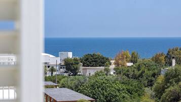Une vue sur la côte, avec une rangée de coins salons extérieurs abrités, un ciel bleu dégagé et la mer en arrière-plan.