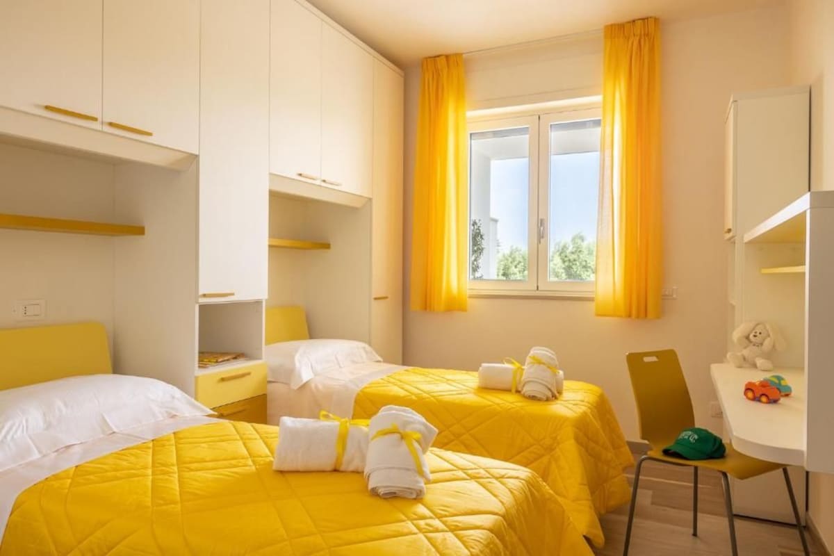 Ein Hotelzimmer mit zwei Betten, einem Schreibtisch und einem Sessel.