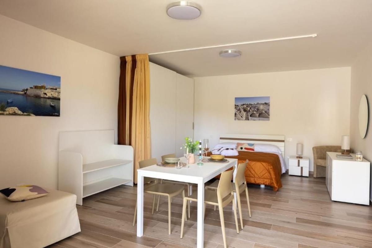 Ein Hotelzimmer mit Bett, Nachttisch, Stuhl und Esstisch mit Stühlen.