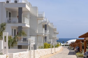 Eine Reihe moderner mehrstöckiger Gebäude mit Balkonen, eine Steinmauer und freier Blick auf das Meer.