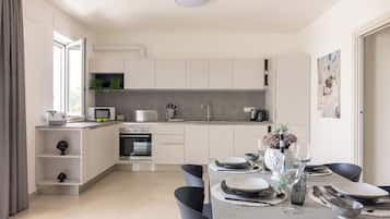 A modern kitchen with white cabinets, a built-in oven, and a dining area with a table set for four.