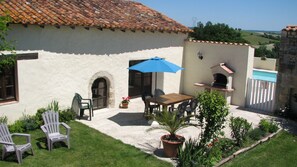 A patio with a table and chairs, a blue umbrella, and a barbecue grill. - Holiday Home 'Limerac, Cottage' with Shared Pool, Shared Terrace and Wi-Fi (Salles-Lavalette)