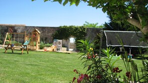 A backyard with a swing set, playhouse, and a fenced area with a climbing wall. - Holiday Home 'Limerac Pigeonnier' with Shared Pool, Shared Terrace and Wi-Fi (Salles-Lavalette)