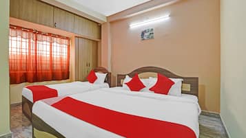 A hotel room with two beds, a window with curtains, a painting on the wall, and a ceiling light.