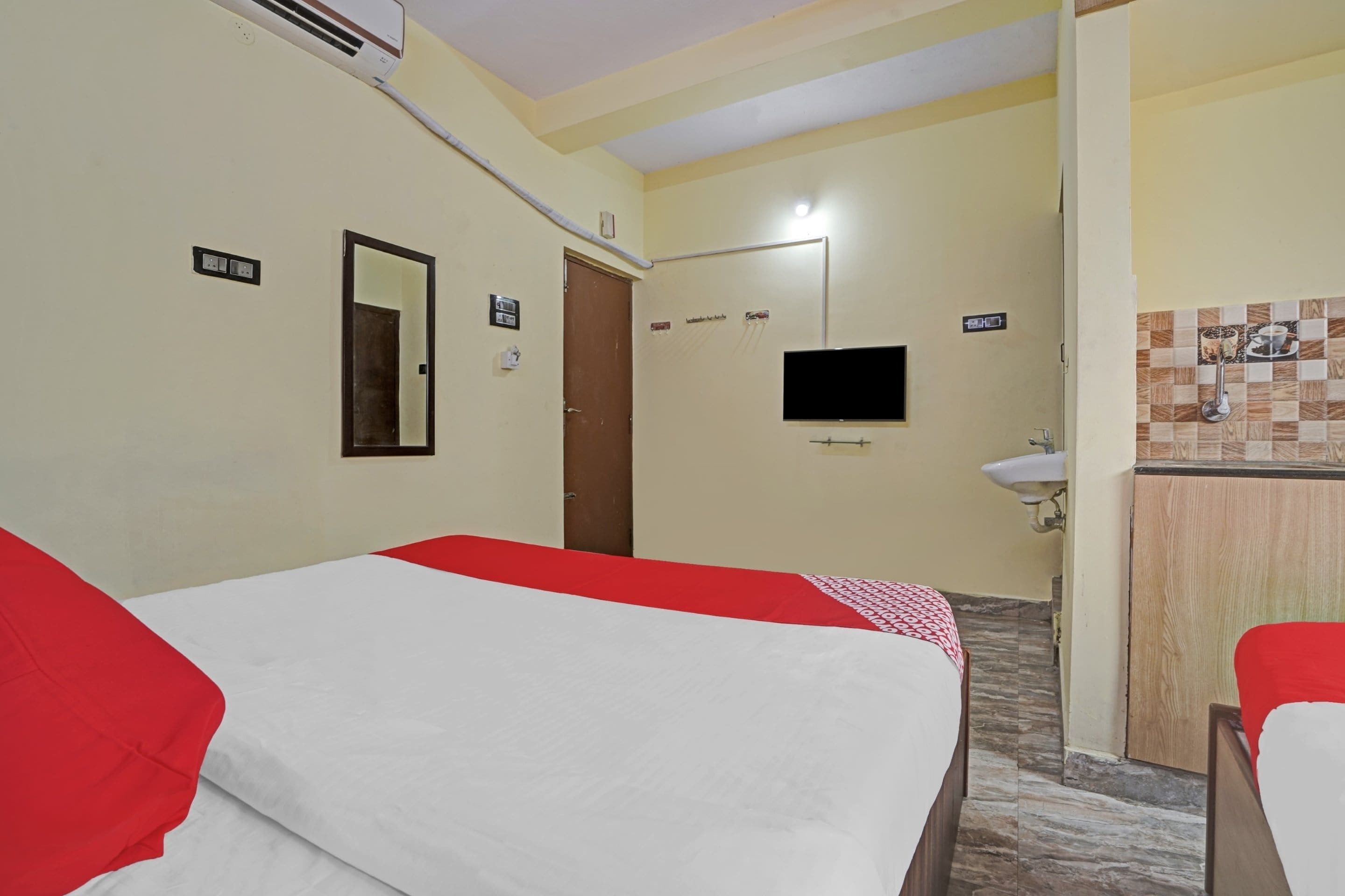 Una habitación de hotel con cama, televisión, baño y una pequeña kitchenette.