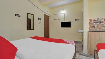 Una habitación de hotel con cama, televisión, baño y una pequeña kitchenette.