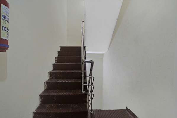 Una escalera con barandilla de metal, que conduce a un rellano con pared blanca.
