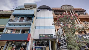 Un immeuble à plusieurs étages, avec une devanture portant l’inscription « SPORTSCENTER » et une enseigne indiquant « T.MAGAR RESIDENCY », proposant des chambres à la location journalière ou mensuelle.