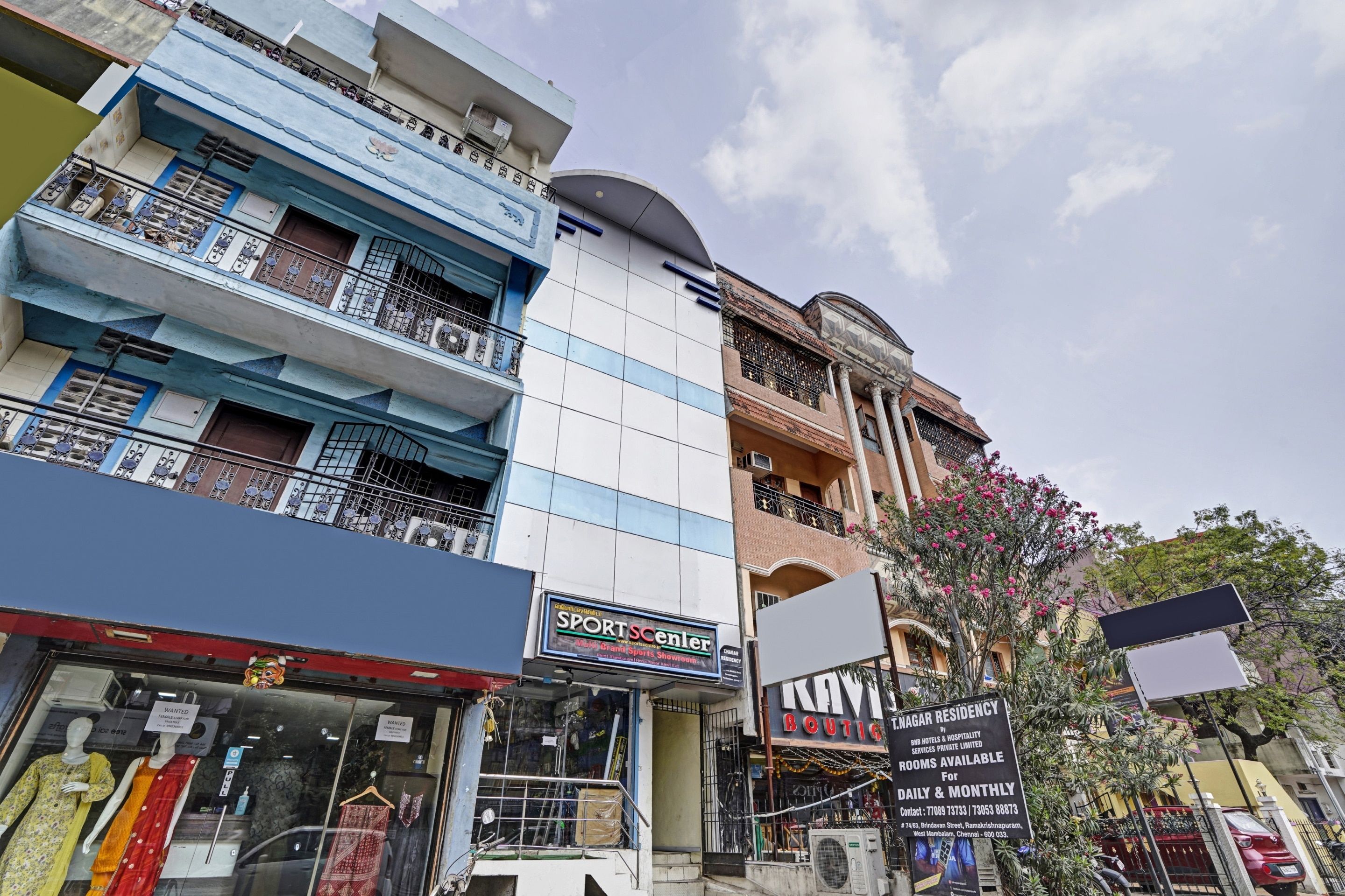 A multi-story building with various shops on the ground floor, including a sports center and a boutique.