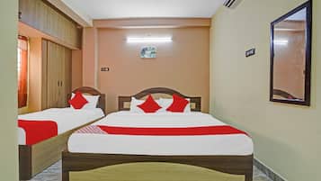 A hotel room with two beds, a ceiling fan, an air conditioning unit, a small painting on the wall, and a mirror.