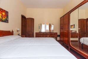 A hotel room with a large bed, wooden wardrobe, and a full-length mirror. - UR NEST Tullio Levi Civita - Prestigious 3 bedroom apartment in the first hills of Bologna (Bologna)