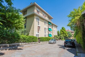 A multi-story building with a flat roof, surrounded by greenery and parked cars. - UR NEST Tullio Levi Civita - Prestigious 3 bedroom apartment in the first hills of Bologna (Bologna)