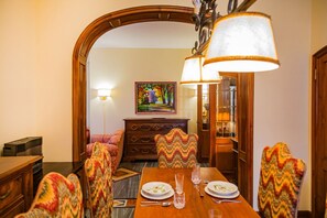 A dining area with a wooden table set for four, flanked by patterned chairs, a painting on the wall, and a lamp above. - UR NEST Tullio Levi Civita - Prestigious 3 bedroom apartment in the first hills of Bologna (Bologna)