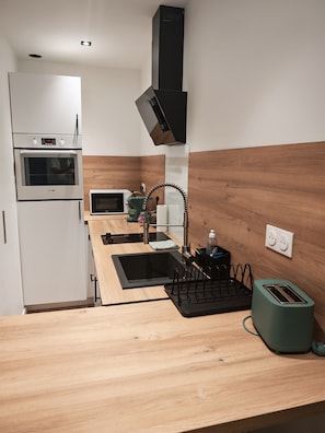 Eine kompakte Küche mit Backofen, Mikrowelle und Spüle inklusive modernem Wasserhahn.