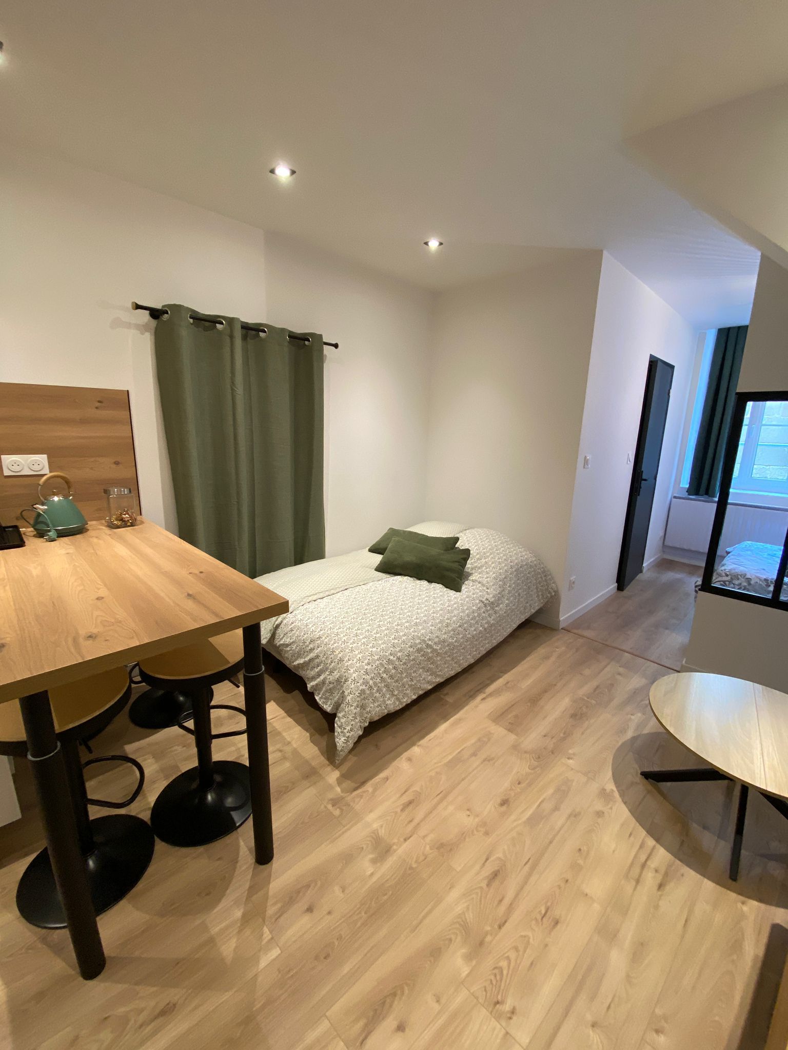 Ein gemütliches Schlafzimmer mit Bett, Holztablett und einer kleinen Küchenzeile.