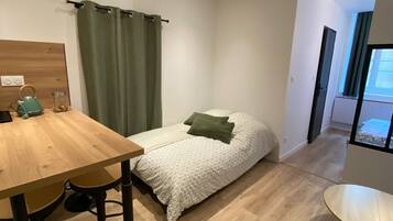 Ein gemütliches Schlafzimmer mit Bett, Holztablett und einer kleinen Küchenzeile.