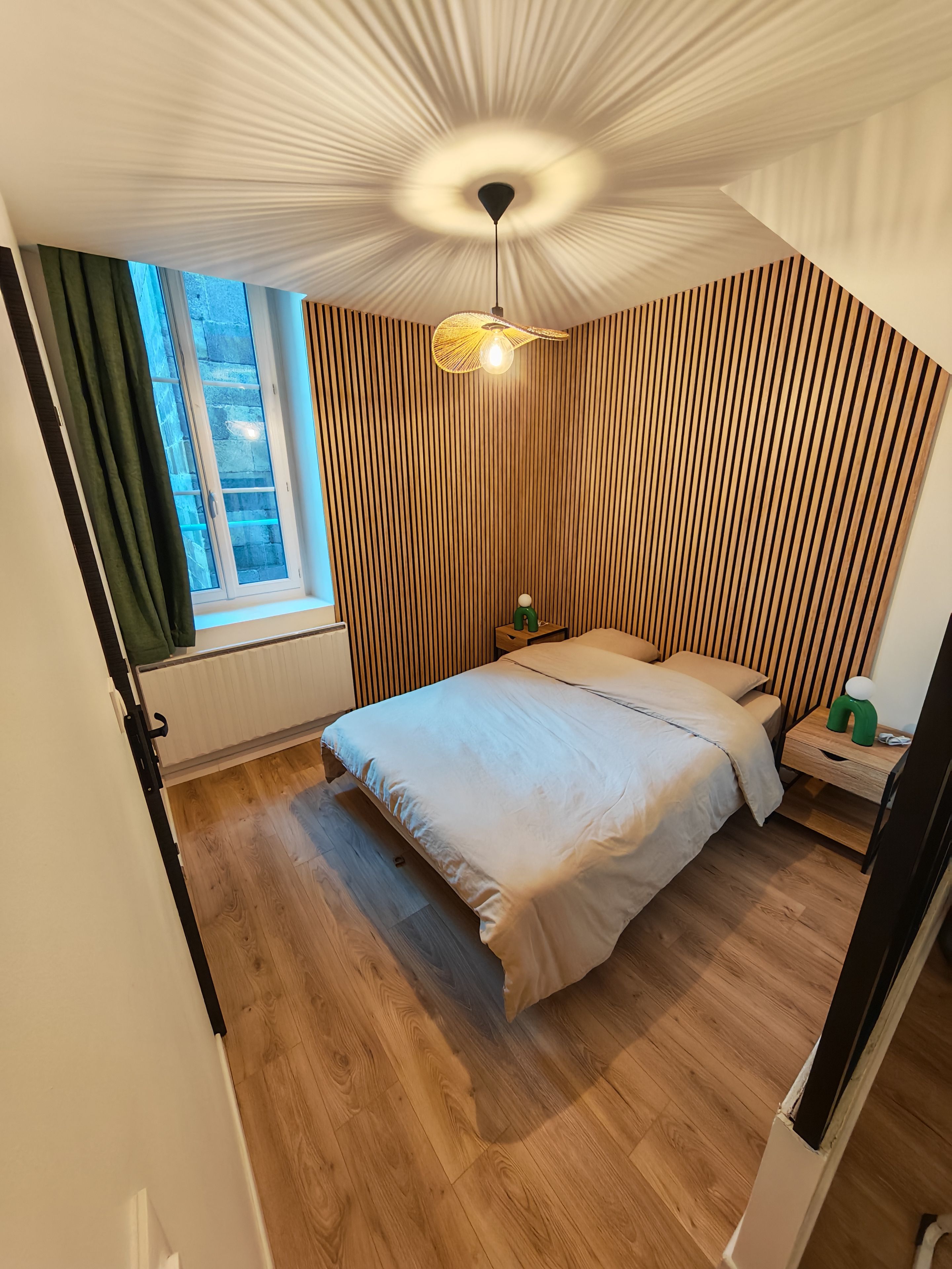 Une chambre à coucher avec un lit, une fenêtre, un ventilateur de plafond et une table de chevet.