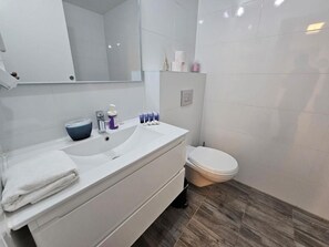 A modern bathroom with a white vanity, a sink, a mirror, and a toilet. - Saviony view  (Jerusalem)