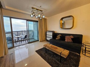 A modern living room with a sofa, a coffee table, a mirror, and a view through a glass door to an outdoor balcony. - Saviony view  (Jerusalem)