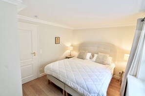 Ein Schlafzimmer mit einem Bett, Nachttischen, einer Tür und einem Wandbild.