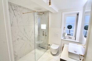 Ein modernes Badezimmer mit einer Duschkabine aus Glas, einer weißen Toilette und einem Waschbecken mit Spiegel.