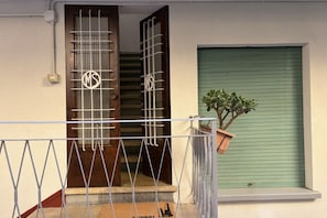 A residential entrance with a metal gate, a wooden door, a staircase, and a green shutter door. - UR NEST San Vitale - Delightful one-bedroom apartment with a separate kitchen under the Two Towers (Bologna)