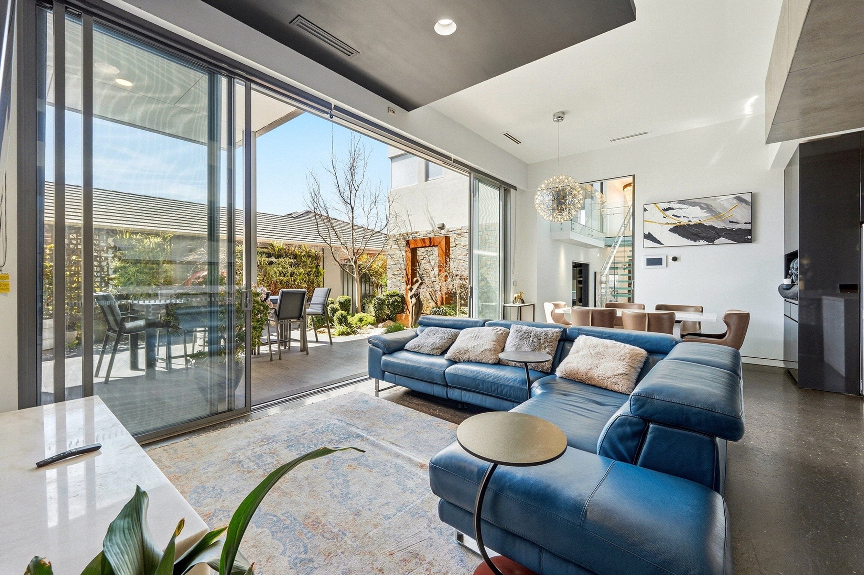 A modern living room with a blue sofa, a dining area, and a kitchen.