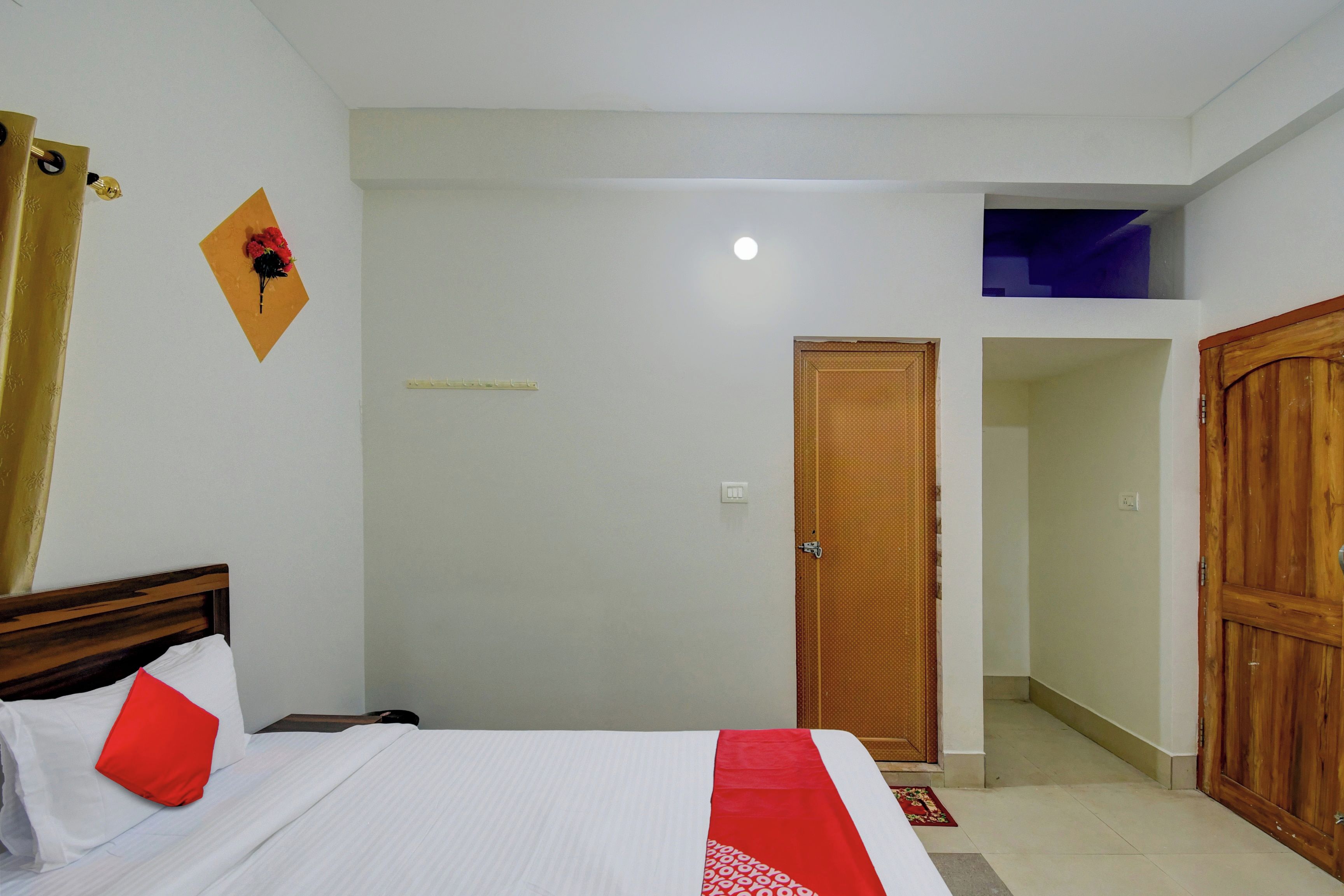 Une chambre à coucher avec un lit, une porte en bois, une petite fenêtre et un luminaire fixé au mur.