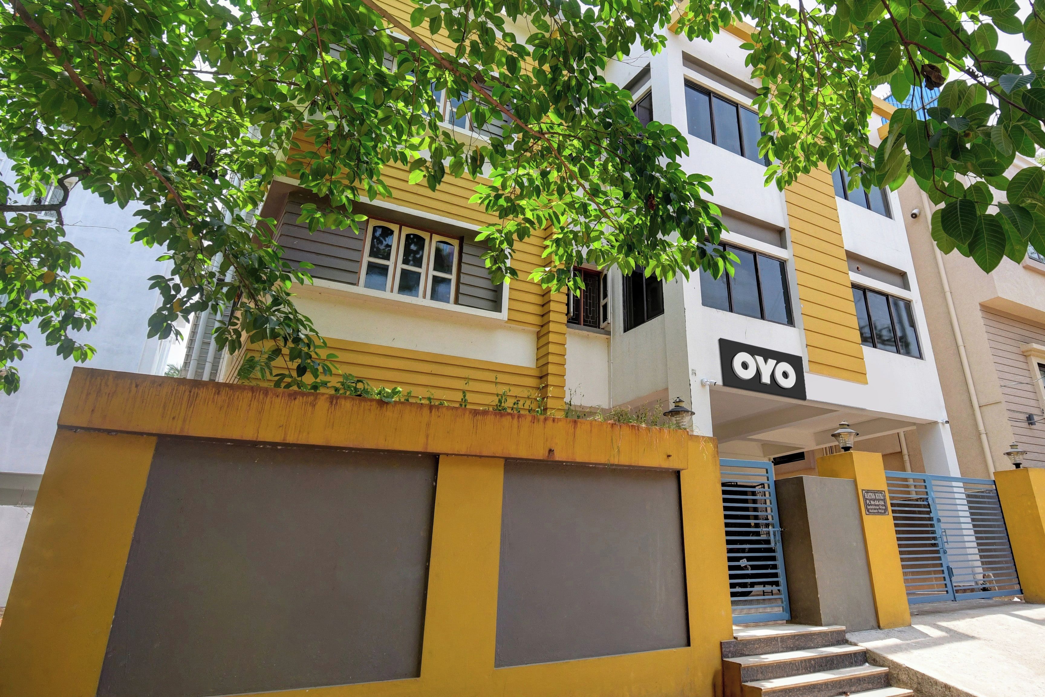 Un immeuble à plusieurs étages, doté d’une façade jaune et blanche, d’une entrée bien visible avec un portail bleu et d’une enseigne sur laquelle on peut lire « OYO ».
