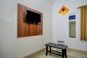 A room with a mounted television, a small table, a mirror, and a decorative item on the wall. - Hotel O Anvi (Bhubaneshwar)