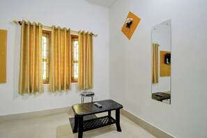 A room with a window, a mirror, and a small table with a remote control. - Hotel O Anvi (Bhubaneshwar)
