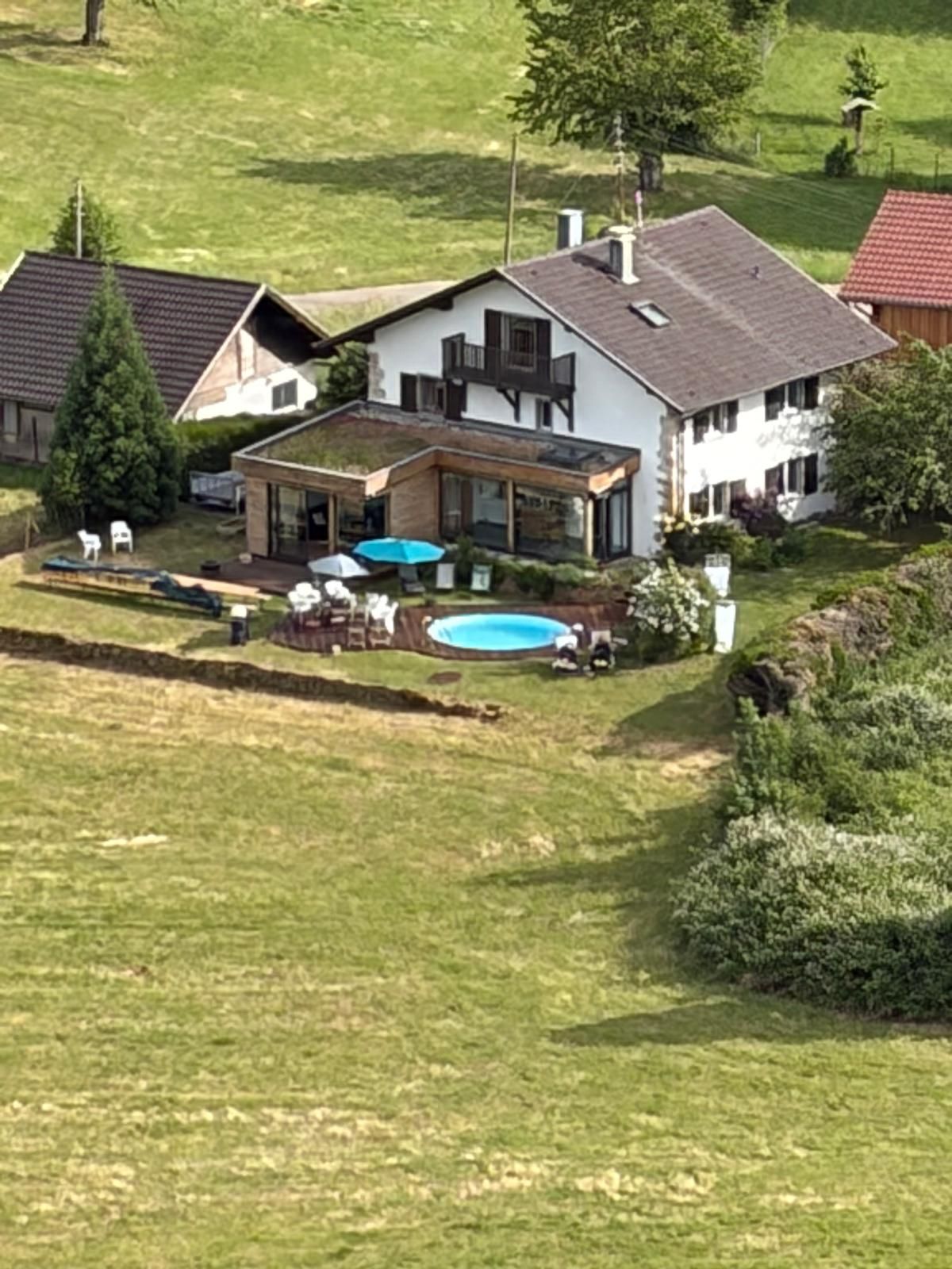 Una propiedad residencial con piscina, un porche cubierto y un amplio jardín.