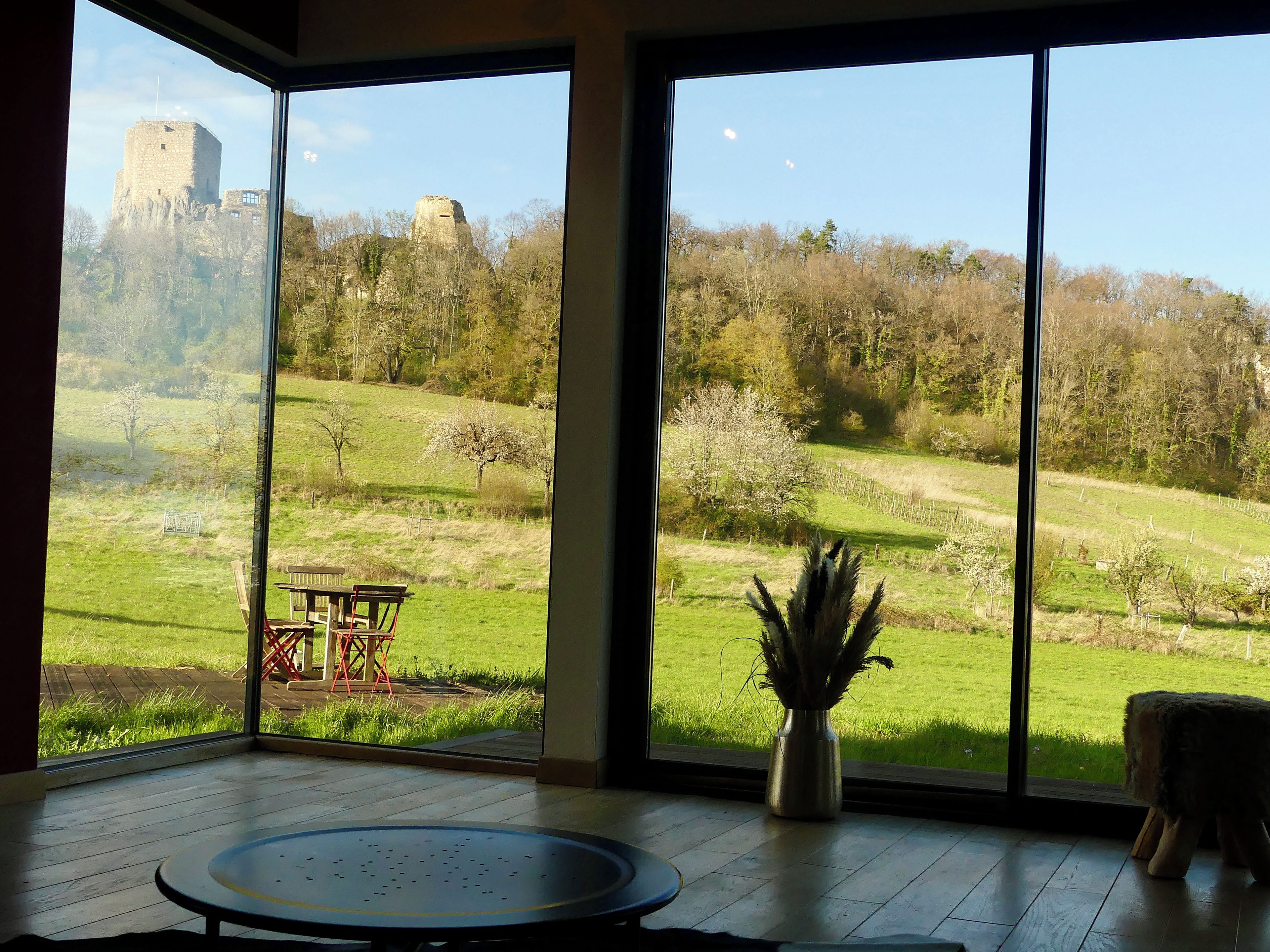 Una habitación con ventanas amplias que ofrecen vistas a un castillo y un paisaje cubierto de césped.