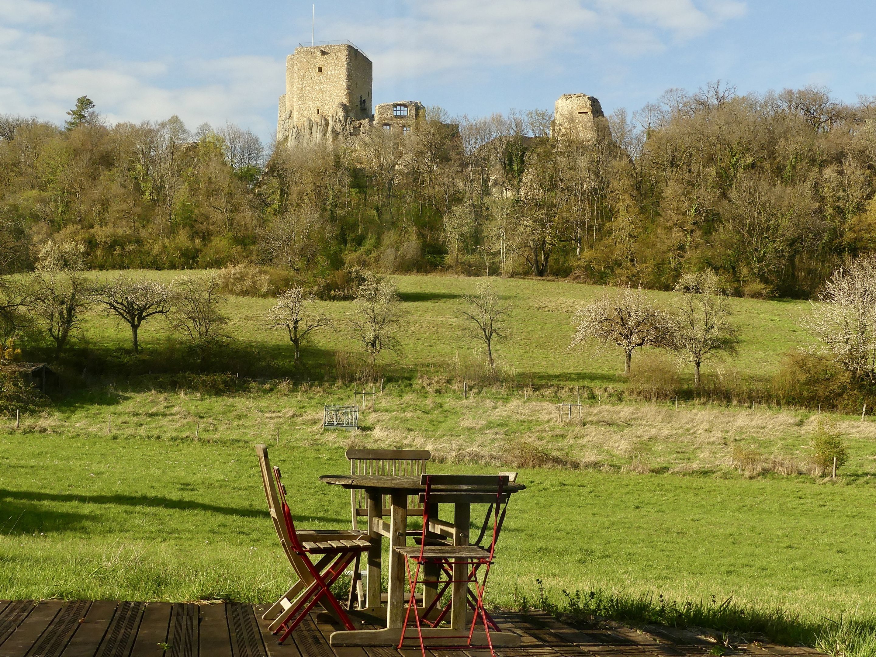 A picnic table with chairs in a grassy field with a castle in the background.